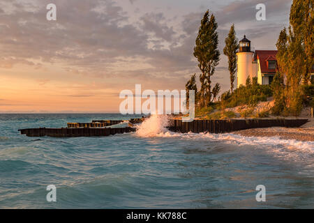 Waves crash along the Lake Michigan shore in front of Point Betsie Lighthouse, during sunset Stock Photo