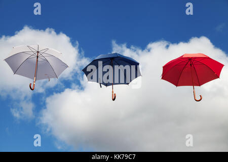 Three Floating Umbrellas in White, Dark Blue and Red Stock Photo