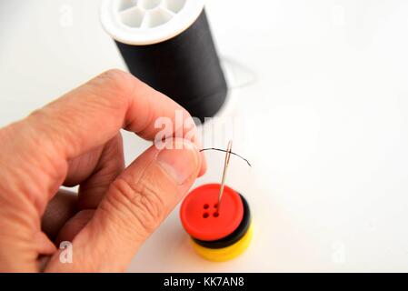 hand threading a needle with black thread Stock Photo