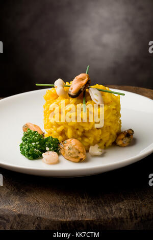 photo of delicious risotto with saffron and seafood on wooden table Stock Photo