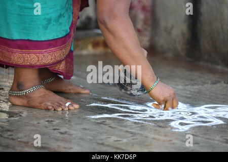 Indische Frau zeichnet ein Kolam auf den Boden vor einem Tempel - Temple painting - Indian woman draws a kolam on the floor in front of a Temple Stock Photo