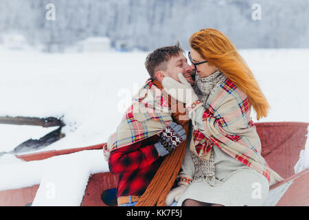 Couple Lovers Sensitive Stroking Cheek Sitting Boat Snowfall Winter Christmas Wrapped Plaid. Stock Photo