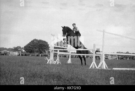 1940s, historical picture, eventing competition, a young lad on a horse jumping a fence, showing good technique and position on the horse,  England, UK. Probably common at this time, is the fact that he is wearing no protective headgear, Stock Photo