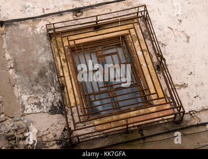 Ancient window with rusty and battered security grille Stock Photo