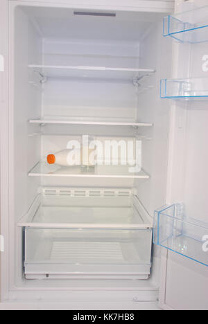 Glass of milk and bottle inside in empty clean refrigerator with opened door Stock Photo
