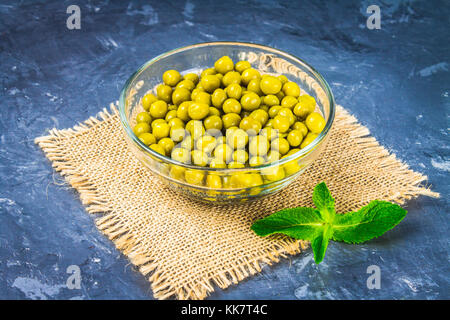 Canned peas in a wooden plate on a gray concrete background Stock Photo