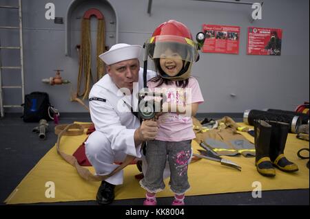 Damage Controlman 1st Class Nathan Alberti, a Sailor aboard the US 7th Fleet flagship USS Blue Ridge LCC 19, gives a fire fighting demonstration to a child during an open ship tour in Tokyo, Japan, 2012. Image courtesy Mass Communication Specialist 3rd Class Fidel C. Hart/US Navy. Stock Photo