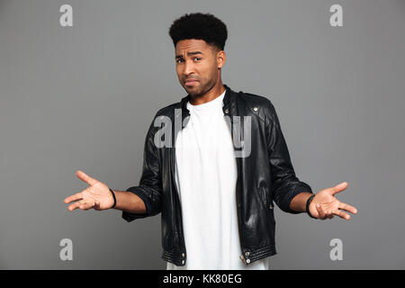 Close-up  photo of amazed afro american man in leather jacket, looking at camera, isolated over gray background Stock Photo