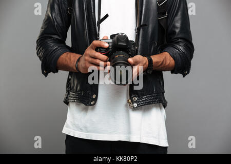 Cropped photo of stylish afro american guy holding digital camera, isolated on gray background Stock Photo