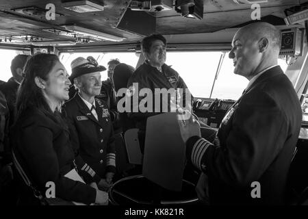 Capt Christopher Bolt, right, commanding officer of the US Navy's only forward-deployed aircraft carrier USS Ronald Reagan CVN 76, explains flight deck operations to Japanese Prime Minister Shinzo Abe, center, during a visit to the ship, Waters South Of Japan. Image courtesy Mass Communication Specialist 3rd Class Ryan McFarlane/US Navy, 2015. Stock Photo