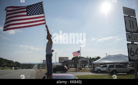 Josh Thurman, from Spring City, Tennessee, waves the American flag from the top of his car at the memorial in front of Armed Forces Recruiting Center in Chattanooga, Tennessee. Thurman had been driving from his home to the memorial everyday to wave the flag. Image courtesy Chief Mass Communication Specialist Michael D. Cole/US Navy, United States, 2015. Stock Photo