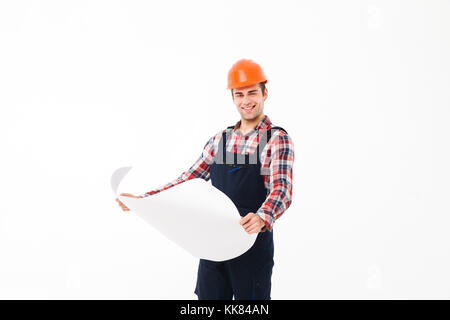 Portrait of a happy young male builder holding paper draft while standing and looking at camera isolated over white background Stock Photo
