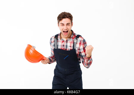 Portrait of a cheerful young male builder celebrating while standing and looking at camera isolated over white background Stock Photo