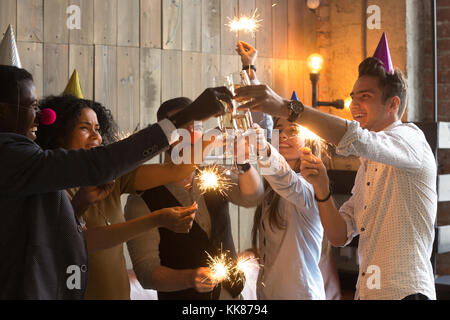 Multi-ethnic young people celebrating New year clinking glasses  Stock Photo