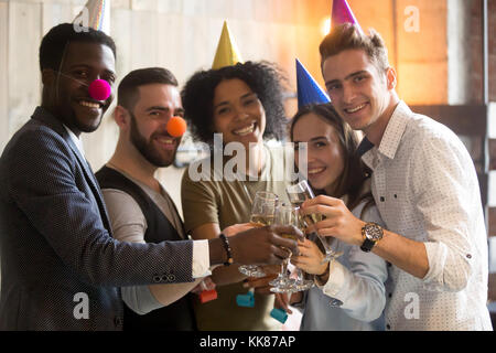 Diverse friends clinking champagne glasses looking at camera cel Stock Photo