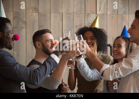 African and caucasian young friends clinking glasses celebrating Stock Photo