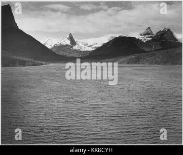 Looking across toward snow-capped mountains, lake in foreground, 'St. Mary's Lake, Glacier National Park, ' Montana. Ansel Adams Photographs of National Parks and Monuments. Image courtesy National Archives, 1941. Stock Photo