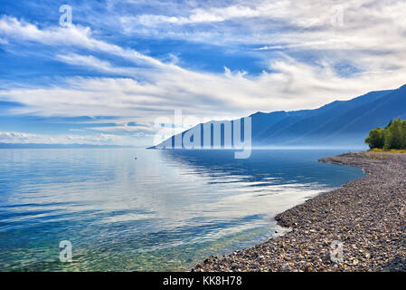 Pebble shore of Lake Baikal and taiga mountains in distance. Irkutsk region. Russia Stock Photo