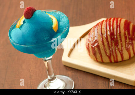 bread on a wooden plate and a glass of ice-cream with raspberry and lemon Stock Photo