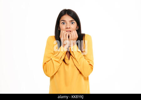 Photo of shocked scared young lady in yellow shirt standing isolated over white background. Looking camera. Stock Photo