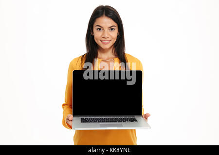 Portrait of young friendly woman showing blank screen laptop computer isolated over white background Stock Photo