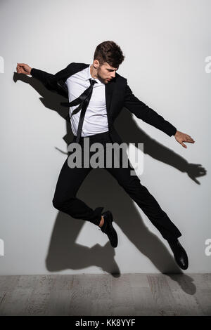 Full length photo of handsome caucasian man in black suit flying over white background Stock Photo