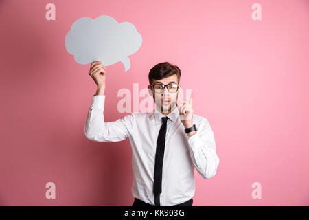 Portrait of an excited smart man in white shirt and eyeglasses having and idea while standing and holding blank paper speech bubble above his head iso Stock Photo