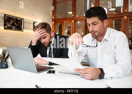 Two handsome bisinessman in formal wear working together while trying to solve problem in office Stock Photo
