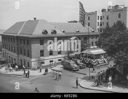 A photograph from the St George Library dedication ceremony, in the photograph the street is closed off and a crowd is gathered around the temporary stage that was constructed in front of the library, the library is a branch of the New York Public Library that was opened in 1907, it is the largest library on Staten Island, New York, 1952. From the New York Public Library. Stock Photo