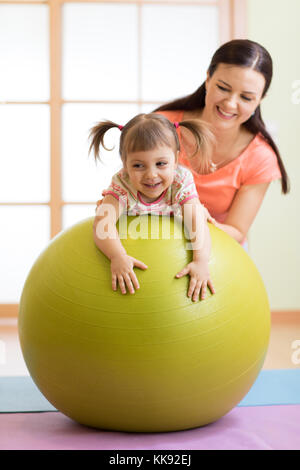 Mother with happy child doing exercises with gymnastic ball at fitness class. Concept of caring for the baby's health. Stock Photo