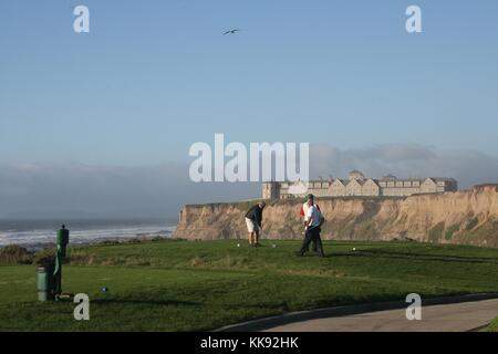 A photograph of a group of golfers teeing off on one of the golf courses at the Ritz Carlton Half Moon Bay Hotel, the hotel is situated atop a cliff and overlooks the ocean and the golf course, Half Moon Bay, California, 2014. Stock Photo