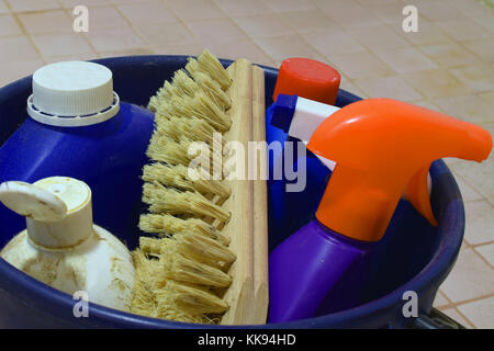 Close up of cleaning items in blue plastic bucket on dirty bathroom floor. Stock Photo