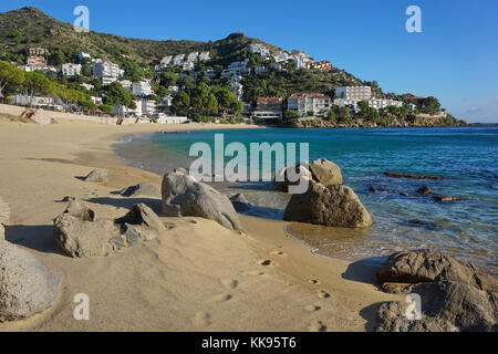 Spain Costa Brava, sand and rocks on the sea shore with buildings in background, Canyelles Petites beach, Roses, Girona, Catalonia, Mediterranean Stock Photo