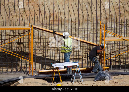 Two workers in a building construction under a bright sun. Stock Photo