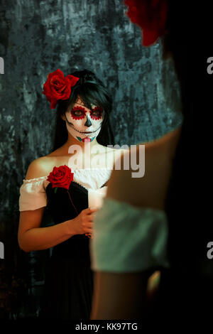 Halloween photo of woman with makeup on face with red flowers Stock Photo
