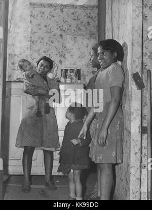 Black and white photograph of three young African-American women standing in the hallway of a home, one holding an infant, a young girl with them, Norfolk, Virginia, March, 1940. From the New York Public Library. Stock Photo