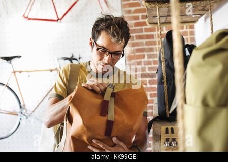 A customer in a bike shop, looking at a backpack. | usage worldwide, Royalty free: For comercial usage price on demand. Stock Photo
