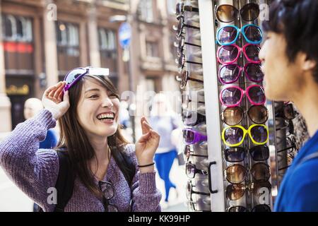 A Japanese woman trying on sunglasses in London, a summer tourist visitor. | usage worldwide, Royalty free: For comercial usage price on demand. Stock Photo