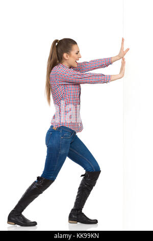 Young woman standing in jeans, black boots and lumberjack shirt. Side view.  Full length studio shot isolated on white Stock Photo - Alamy