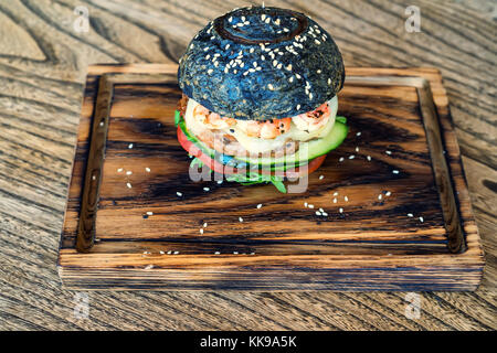 Black burger with prawns on wooden board Stock Photo