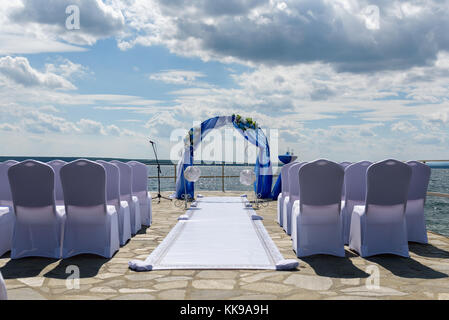 Wedding arch with empty chairs on the background of the lake. Stock Photo