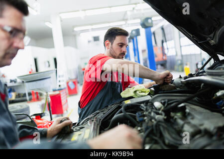 Mechaniker und sein Assistent untersuchen den Fahrzeugboden mit Blitzlicht. Auto  Auto Reparatur Service Center. Professioneller Service Stockfotografie -  Alamy
