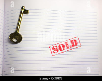 key on a blank paper page with the red rubber stamp sold showing property sales copy space Stock Photo