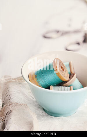 Vintage tea cup filled with antique spools of thread. Stock Photo