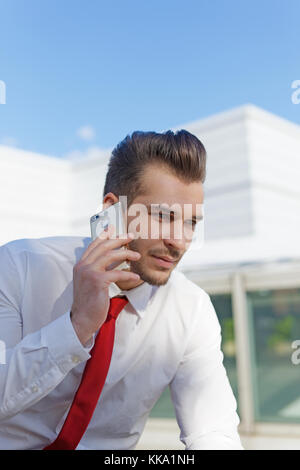 Young smart businessman in formal wear calling outdoors Stock Photo