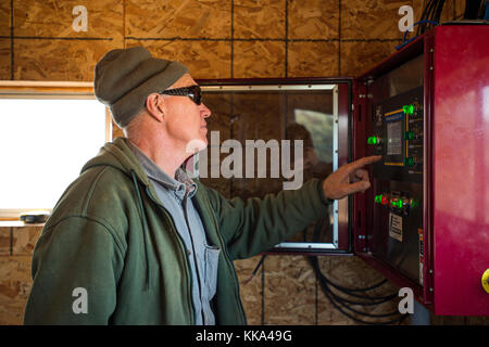 FARMER OPERATING GRAIN STORAGE CONTROL BOARD IN UTICA, MINNESOTA. Stock Photo