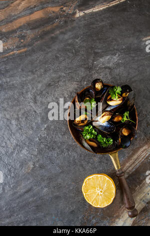 Mussels with herbs in a copper bowl. Seafood. Food at the shore of the French Sea. Dark background Stock Photo
