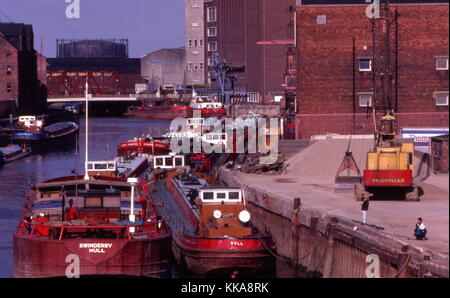 Barges on the River Hull during the 1980s with a Preistman's crane and grab, Kingston upon Hull, Yorkshire, UK. Drypool bridge lowered in the backgrou Stock Photo