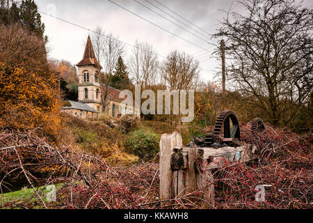 Cast iron gears from Belvedere Mill, with Christ Church, Chalford behind , near Stroud, in the Cotswolds, Gloucestershire, England. Stock Photo