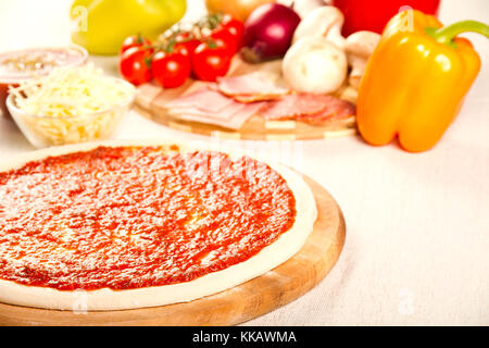 Raw pizza with ingredients in the bacground Stock Photo